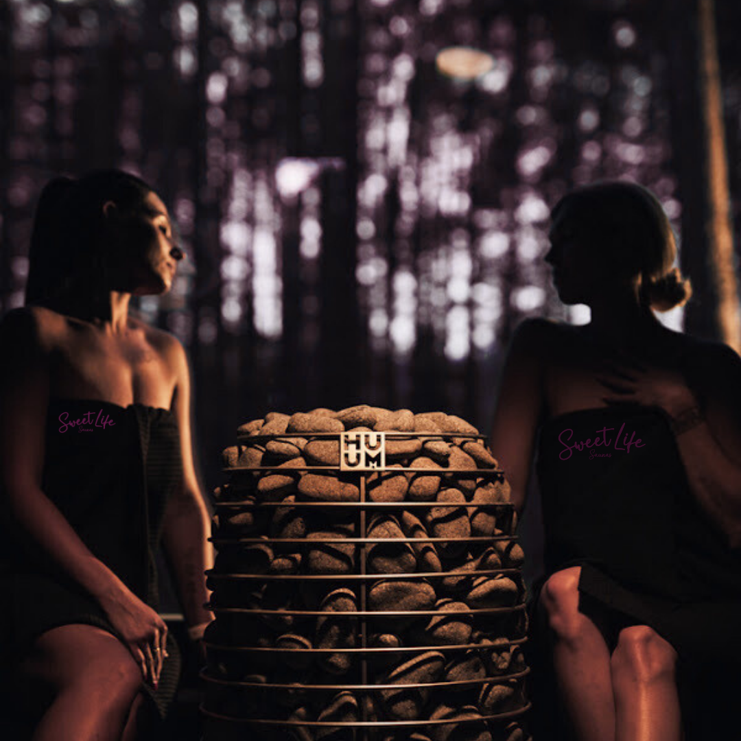 Two people sitting in front of a stone structure with 'HUM' branding, against a blurred background.